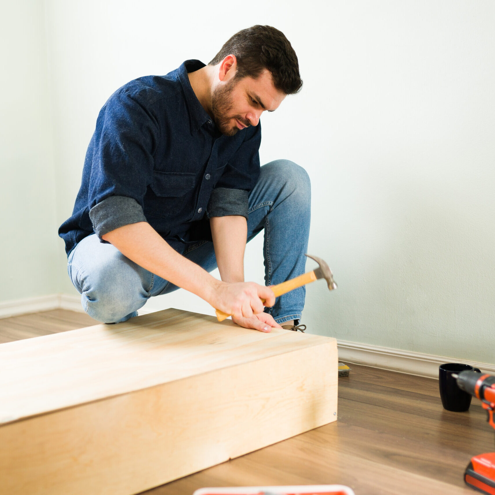 Good-looking young man building himself a new wooden shelf and doing some DIY home renovations